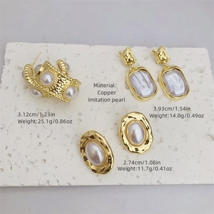 Tre paia di orecchini placcati oro 18K con perle su espositore in pietra bianca testurizzata