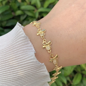 Détail du bracelet noeud plaqué or 18K avec zircons scintillants au poignet féminin