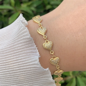 Détail d'un bracelet en forme de cœur plaqué or 18 carats avec oxydes de zirconium au poignet