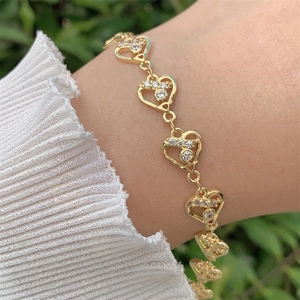 Bracelet cœur élégant plaqué or 18 carats avec zircons porté au poignet, lumière douce