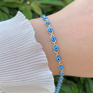 Close-up of golden evil eye bracelet with blue beads on a woman wrist in nature