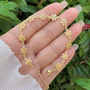 Elegant 18K gold plated copper bracelet with floral zircon charms on hand outdoors