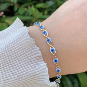 Close-up of a 18K gold plated evil eye bracelet worn on a wrist with nature backdrop