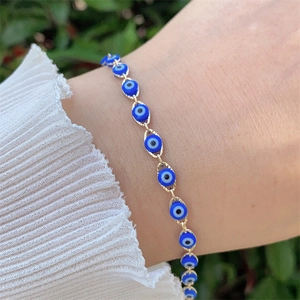 Detail of 18K gold plated Evil Eye bracelet with blue charms on a female wrist