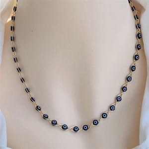 Macro detail of 18K gold plated evil eye necklace featuring deep blue beads on a model