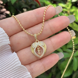 Close-up of 18K gold plated heart necklace with wings and crystal letter F pendant