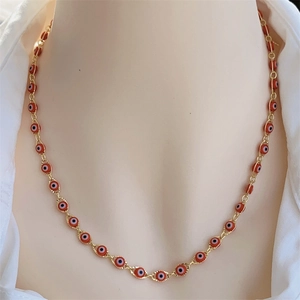 Detail of 18K gold plated necklace with red evil eye charms on a mannequin model
