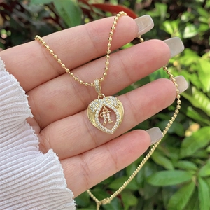 Macro detail of 18K gold plated heart pendant with zircon H letter on bead chain