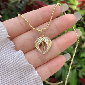 Detail of 18K gold plated heart pendant with zircon musical note on a beaded chain