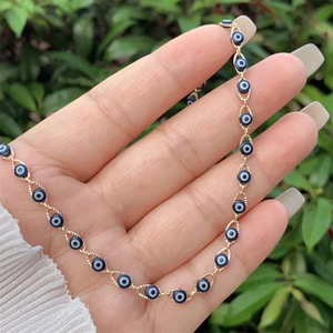 Macro detail of 18K gold plated evil eye bracelet with blue enamel beads on human hand