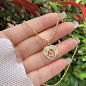 Detail of 18K gold heart pendant necklace with zircon Q letter in outdoor light