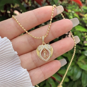 Detail of 18K gold-plated heart pendant with letter R and sparkling cubic zirconia stones