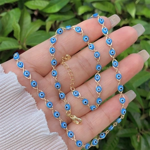 Detail of 18K gold-plated Evil Eye necklace and bracelet set held against nature