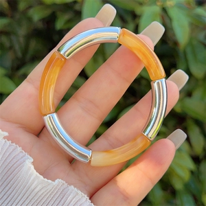 Detail view of a bamboo-style resin elastic bracelet worn on a wrist against nature