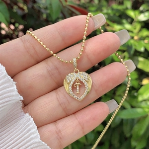 Macro view of 18K gold-plated heart pendant with zircon wings and movable letter T