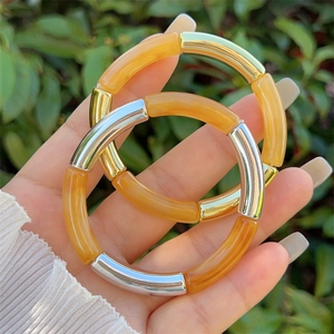 Detailed macro view of honey-yellow resin bamboo-tube stretch bracelets with metallic beads