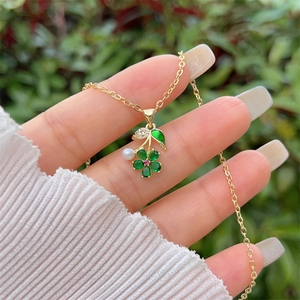 Detail der 18K vergoldeten Blumenkette mit smaragdgrünen Herzsteinen und einer weißen Perle