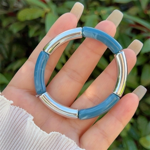 Close-up of blue marble resin and silver metal tube bracelet held in hand