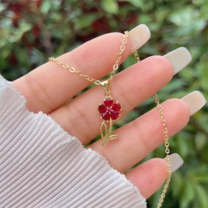 Detail einer Blumenhalskette mit roten Edelsteinblättern und goldener Kette