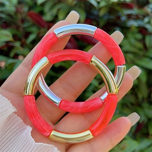 Detail of coral pink resin and metal tube bangles in a stackable bohemian style