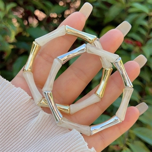 Dettaglio dei braccialetti in resina stile bambù con giunture in metallo oro e argento