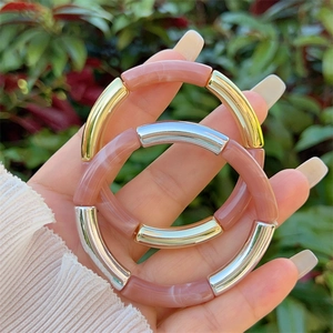 Detail of pink marble resin bangles with gold and silver accents on a female hand