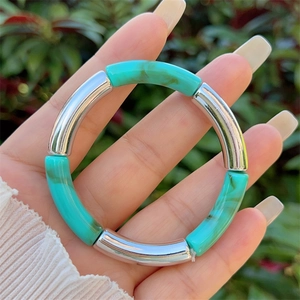 Close-up of resin marble effect and silver metal tubes on an elastic bracelet