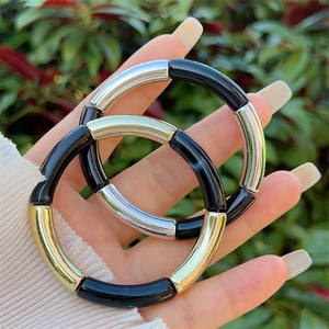 Detail of bamboo-style elastic resin bracelets in black, gold, and silver finishes