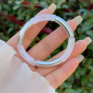 Detail of silver metal and white marble resin elastic tube bracelet on hand