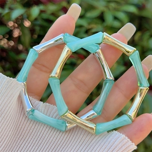 Dettaglio ravvicinato di bracciali stile bambù in resina azzurra e metallo nella natura