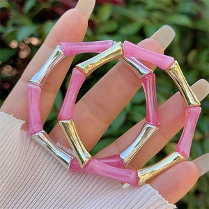 Bracciali in resina rosa stile bambù con accenti oro e argento indossati da modella
