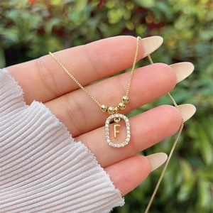 Detail view of gold-plated letter F pendant with zircon stones on a thin box chain