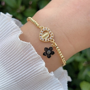 Close-up of 18K gold-plated beaded bracelet with zircon heart and black floral charm
