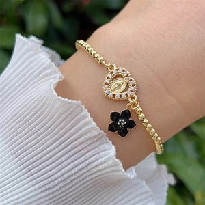 Detail of 18K gold plated beaded bracelet with St. Jude medal and black enamel flower