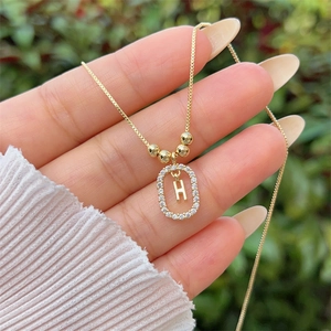 Macro detail of 18K gold plated letter H pendant with shimmering micro-paved zircons
