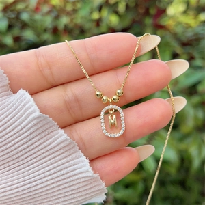 Close-up of 18K gold plated letter M pendant with zircon stones and polished beads