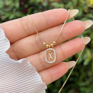 Macro view of 18K gold plated letter X pendant necklace with sparkling zircon pavé