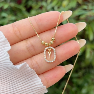 Detail of 18K gold plated necklace with a sparkling diamond-set letter Y pendant held by hand