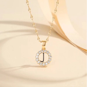 Λήψη macro χρυσού κολιέ με κυκλικό μενταγιόν με το γράμμα J και πέτρες ζιργκόν