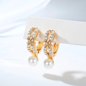 Close-up of gold hoop earrings with zircon floral accents and elegant pearl drop