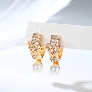Detail view of gold-plated heart earrings with zircon inlay and elegant pearl pendants