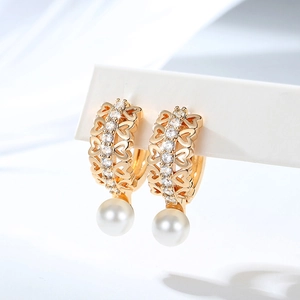 Detail of gold-plated hoop earrings with hollow heart patterns, zircons and pearls