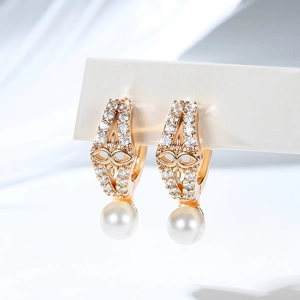Macro shot of gold-plated hoop earrings with micro-set zircons and a white pearl drop