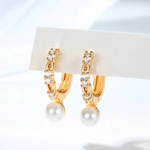 Macro detail of gold-plated hoop earrings with sparkling zircons and elegant white pearls