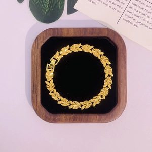 Vue détaillée des maillons de bracelet en forme de cœur dorés 24 carats sur velours