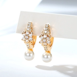 Macro detail of gold-plated hoop earrings with sparkling zircon flowers and pearl drops