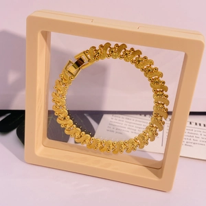 Vue détaillée du bracelet doré pour femmes avec motifs étoilés et fermoir sur un support