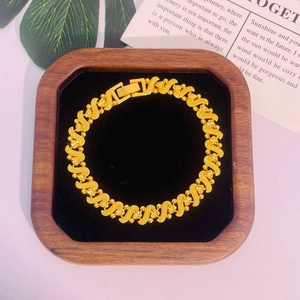 Gros plan d'un bracelet plaqué or 24 carats avec maillons en S et motifs floraux
