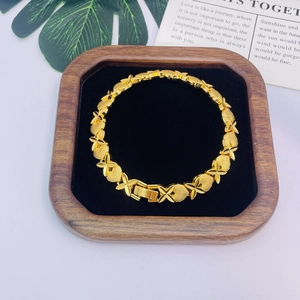 Détail d'un bracelet doré avec maillons cœur et fleur sur un plateau en velours