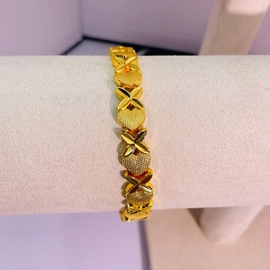 Détail d'un bracelet plaqué or 24K avec motifs de fleurs et de cœurs sur velours gris